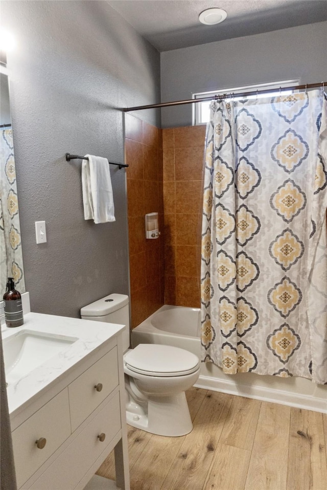 full bathroom with shower / tub combo with curtain, a textured wall, toilet, vanity, and hardwood / wood-style floors