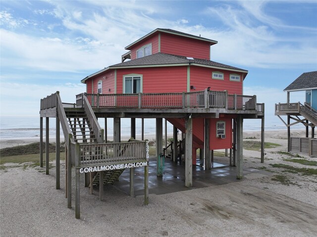 exterior space with stairway, a deck with water view, and roof with shingles