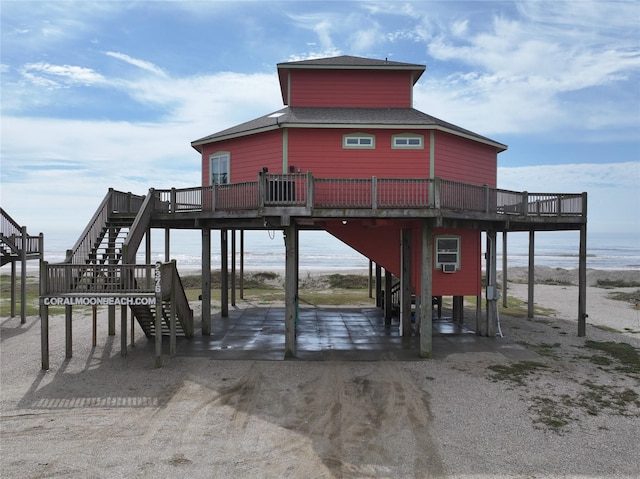 exterior space with roof with shingles, stairway, and a deck with water view