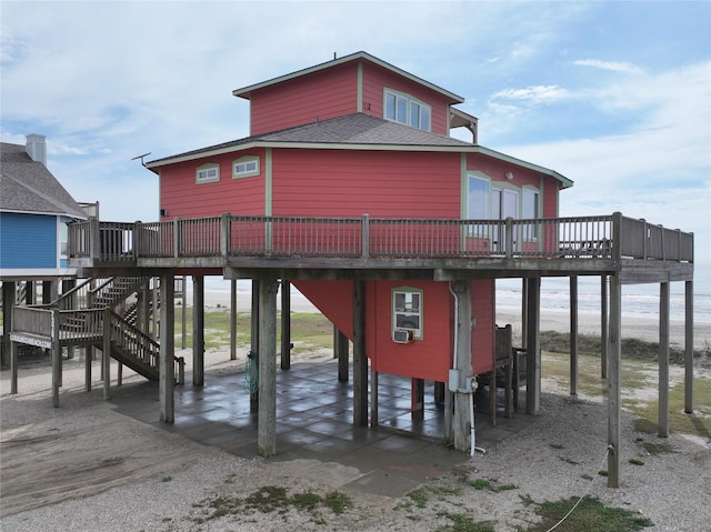 rear view of house with roof with shingles, stairs, a deck, and a patio