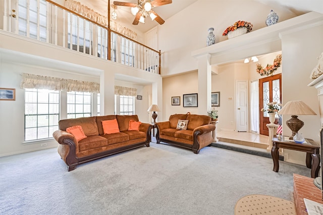 living area with carpet flooring, ceiling fan, and a towering ceiling