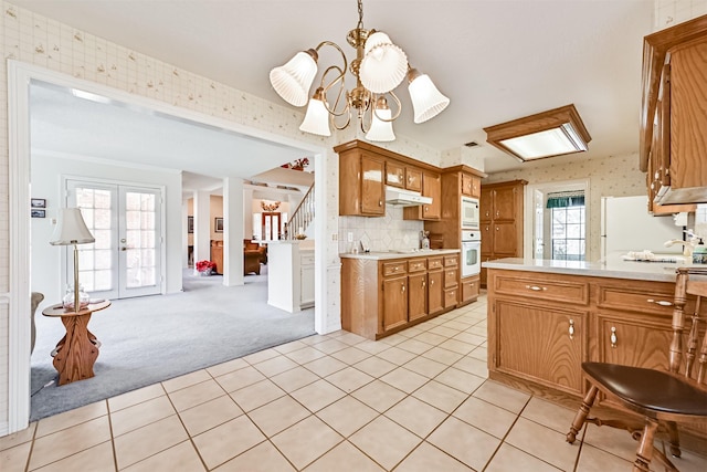 kitchen featuring light carpet, light countertops, white appliances, and wallpapered walls