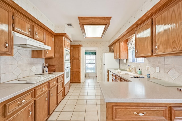 kitchen with visible vents, light countertops, under cabinet range hood, and wallpapered walls