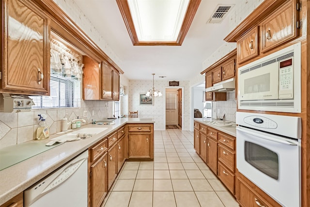 kitchen with light countertops, visible vents, white appliances, a peninsula, and wallpapered walls