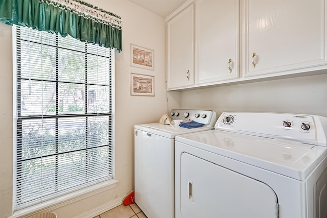 laundry area with cabinet space, plenty of natural light, light tile patterned floors, and washing machine and clothes dryer