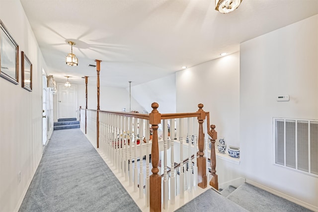 hall with visible vents, light carpet, and baseboards