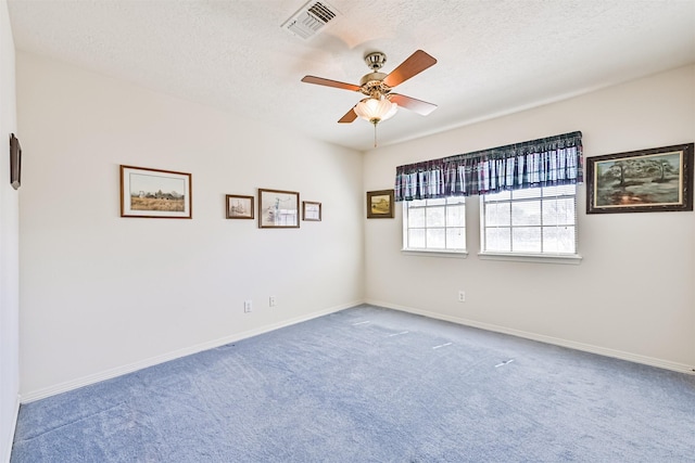 carpeted spare room with baseboards, a textured ceiling, visible vents, and a ceiling fan