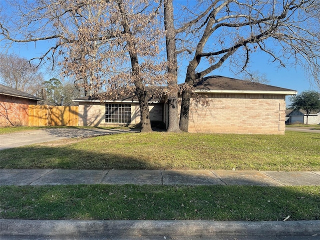 view of front of house with brick siding, fence, and a front lawn