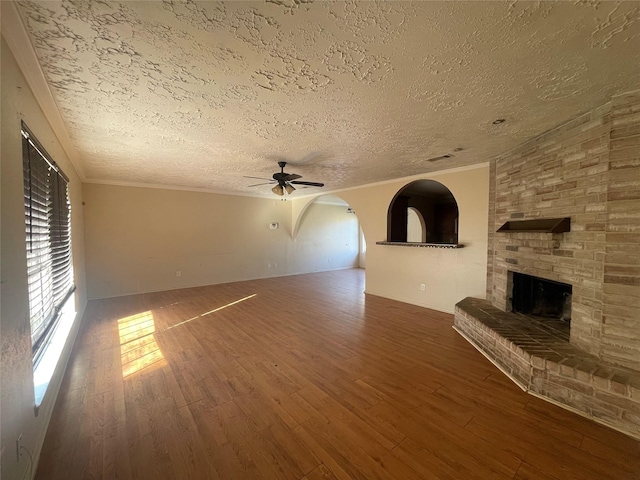 unfurnished living room with ornamental molding, a fireplace, wood finished floors, and a ceiling fan