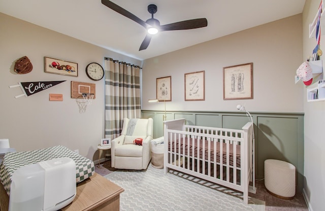 carpeted bedroom with a ceiling fan and a crib