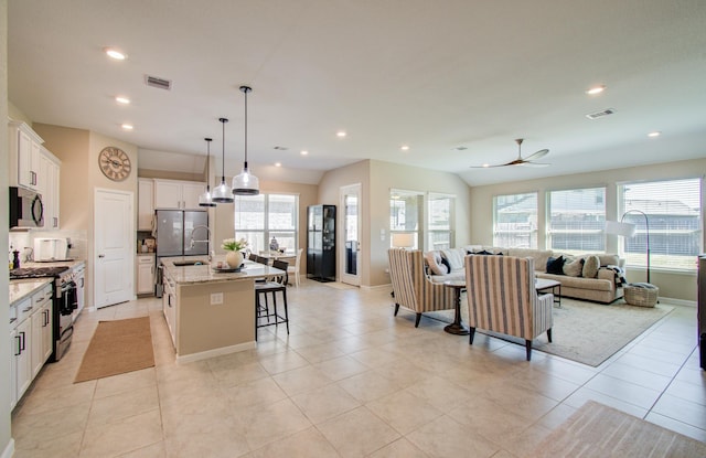 kitchen with stainless steel appliances, a kitchen island with sink, open floor plan, and visible vents