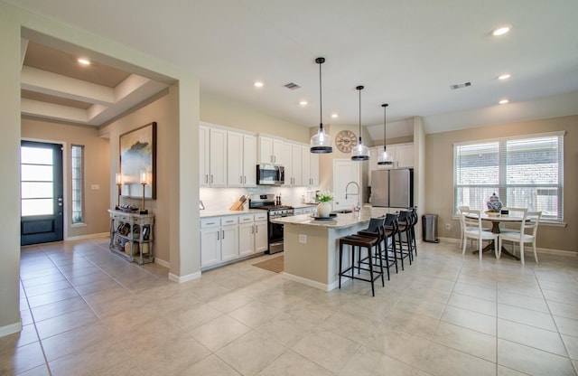 kitchen featuring white cabinets, visible vents, appliances with stainless steel finishes, and a breakfast bar