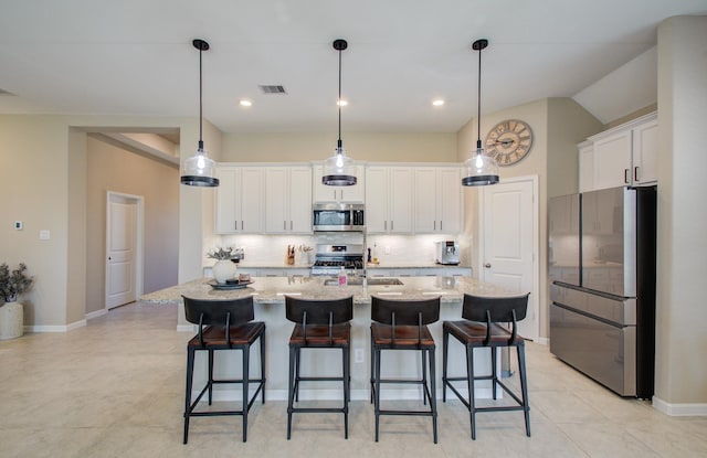 kitchen with visible vents, white cabinets, decorative backsplash, appliances with stainless steel finishes, and a breakfast bar