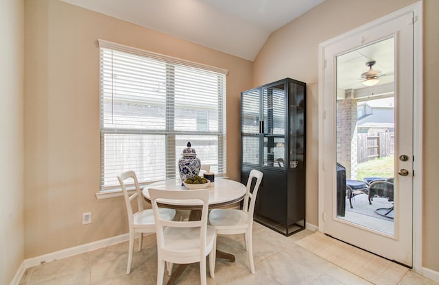 dining area with baseboards, vaulted ceiling, and light tile patterned flooring