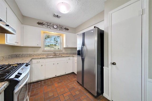 kitchen featuring appliances with stainless steel finishes, white cabinets, visible vents, and a sink