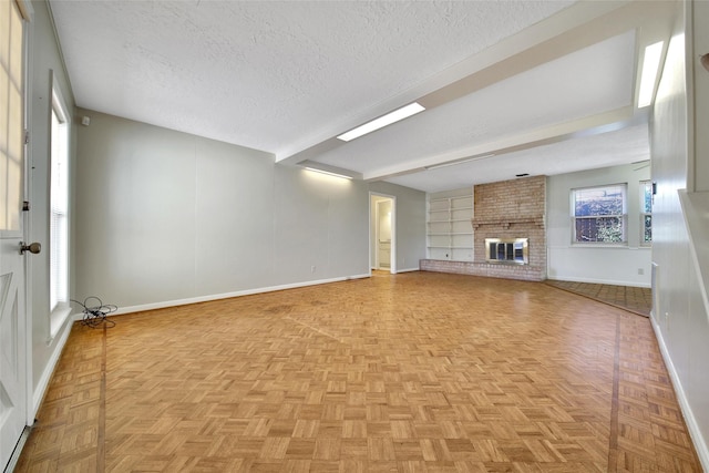 unfurnished living room with a brick fireplace, baseboards, and a textured ceiling