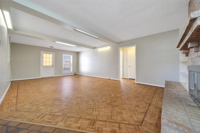 unfurnished living room featuring a fireplace, a textured ceiling, and baseboards