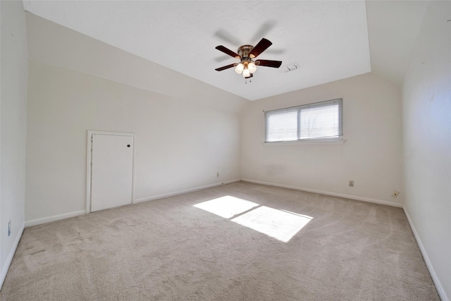 spare room featuring light carpet, baseboards, visible vents, a ceiling fan, and vaulted ceiling