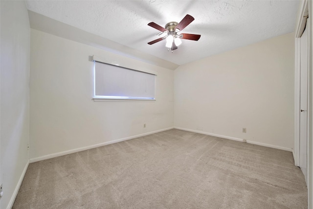 empty room featuring light colored carpet, ceiling fan, a textured ceiling, and baseboards