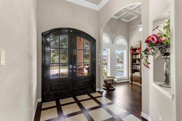 foyer entrance featuring baseboards, coffered ceiling, arched walkways, and french doors