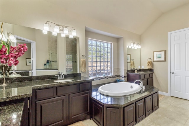 bathroom with lofted ceiling, tile patterned flooring, a garden tub, and a sink