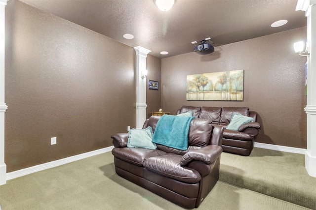 carpeted cinema room featuring baseboards, a textured wall, a textured ceiling, and ornate columns