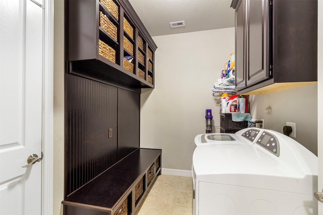 laundry room featuring a textured ceiling, separate washer and dryer, visible vents, baseboards, and cabinet space