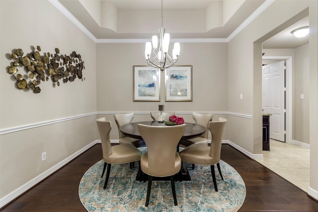 dining space featuring a chandelier, wood-type flooring, a raised ceiling, and baseboards