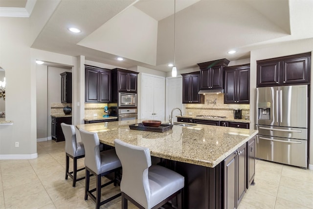 kitchen featuring appliances with stainless steel finishes, decorative backsplash, light stone counters, and light tile patterned flooring