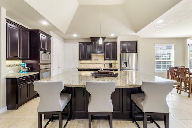 kitchen featuring dark brown cabinetry, visible vents, vaulted ceiling, stainless steel appliances, and pendant lighting