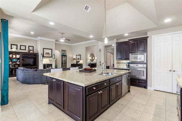 kitchen featuring visible vents, arched walkways, a glass covered fireplace, appliances with stainless steel finishes, and a sink