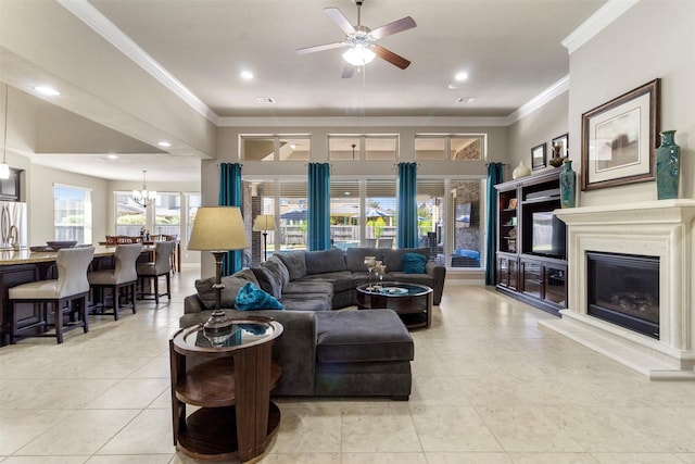 living room featuring a fireplace with raised hearth, light tile patterned floors, recessed lighting, ceiling fan with notable chandelier, and ornamental molding