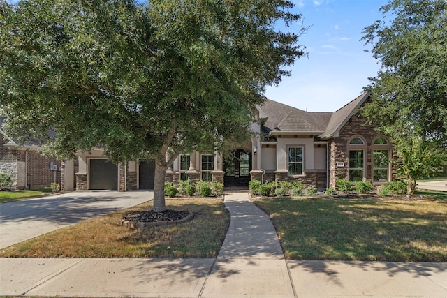 view of front of house with stone siding, a front lawn, concrete driveway, and stucco siding