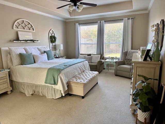 carpeted bedroom with a tray ceiling, crown molding, and ceiling fan