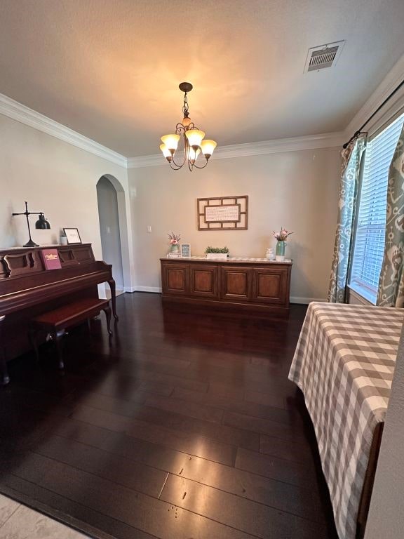 bedroom with ornamental molding, arched walkways, visible vents, and dark wood finished floors