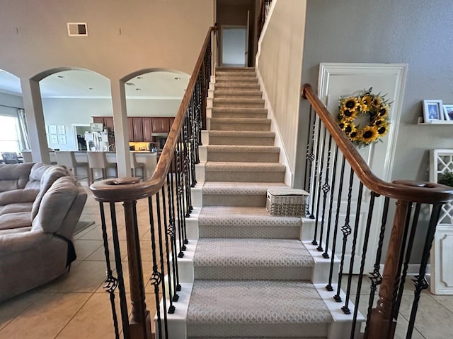 stairway featuring arched walkways, tile patterned flooring, visible vents, and crown molding