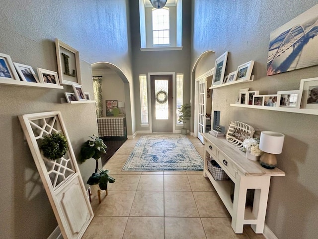 foyer entrance with baseboards, a high ceiling, and tile patterned floors