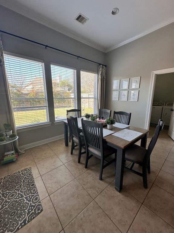 dining room featuring light tile patterned floors, visible vents, ornamental molding, separate washer and dryer, and baseboards