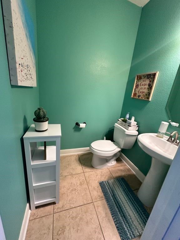 bathroom featuring baseboards, a sink, toilet, and tile patterned floors