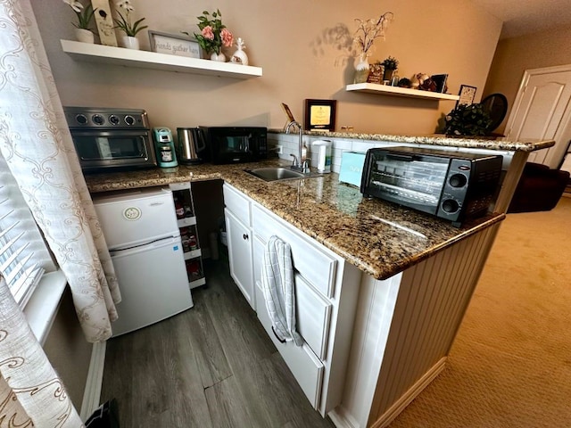 kitchen with dark wood-style floors, open shelves, a sink, and freestanding refrigerator