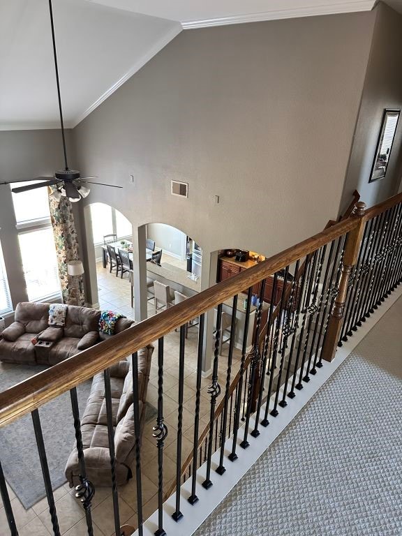 stairway featuring arched walkways, crown molding, ceiling fan, high vaulted ceiling, and tile patterned flooring