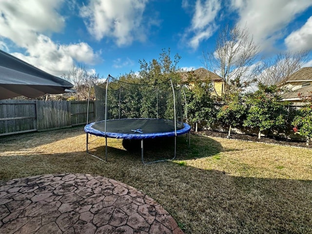 view of yard with a patio area, a fenced backyard, and a trampoline