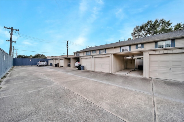 view of vehicle parking featuring fence and community garages