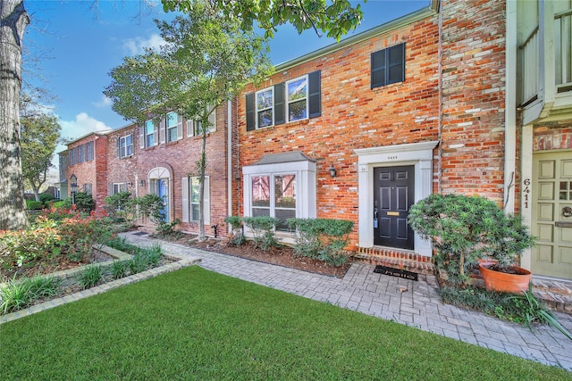 view of property with brick siding and a front yard