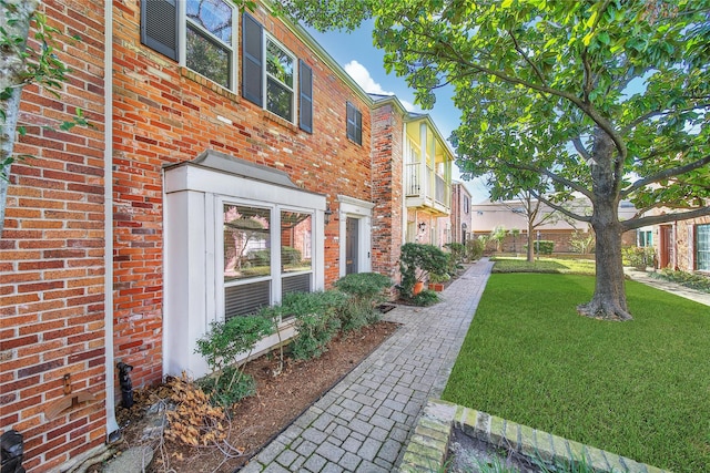 view of side of property with brick siding and a yard