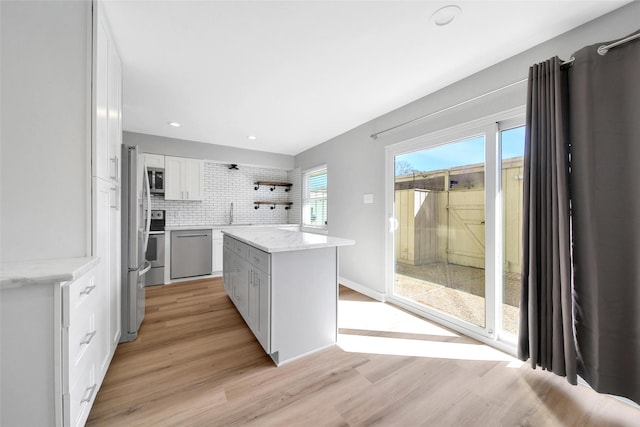 kitchen featuring open shelves, stainless steel appliances, light wood-style flooring, backsplash, and white cabinets