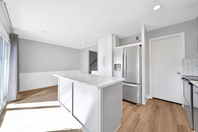 kitchen with light wood finished floors, a kitchen island, white cabinetry, and stainless steel fridge with ice dispenser