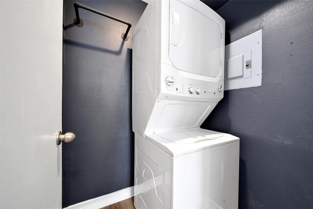 laundry room with baseboards, a textured wall, and stacked washing maching and dryer