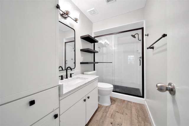 full bath with a stall shower, visible vents, toilet, wood finished floors, and vanity