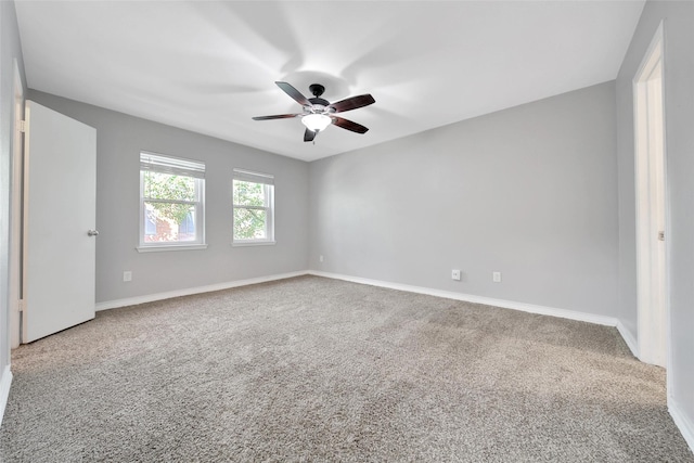 empty room with carpet floors, a ceiling fan, and baseboards